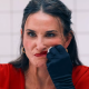 Elisabeth looking frustrated and anxious in front of a mirror, applying more lipstick and smudging it across her face, portraying the pressure of beauty standards and self-image struggles.